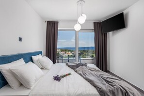 Relax in a spacious room with a large bed, flat-screen TV, and a window offering a view of the surrounding landscape.