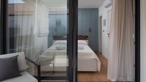 Een moderne slaapkamer met een glazen deur naar een balkon, een bed met witte lakens en een houten hoofdbord.