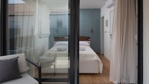 A bedroom with a bed, a sofa, and a sliding glass door leading to a balcony.