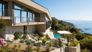 Una casa moderna con fachada de piedra, ventanas grandes y piscina.
