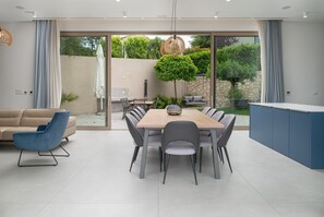 Un espace repas moderne comprenant une grande table, des chaises, un canapé et un coin cuisine.