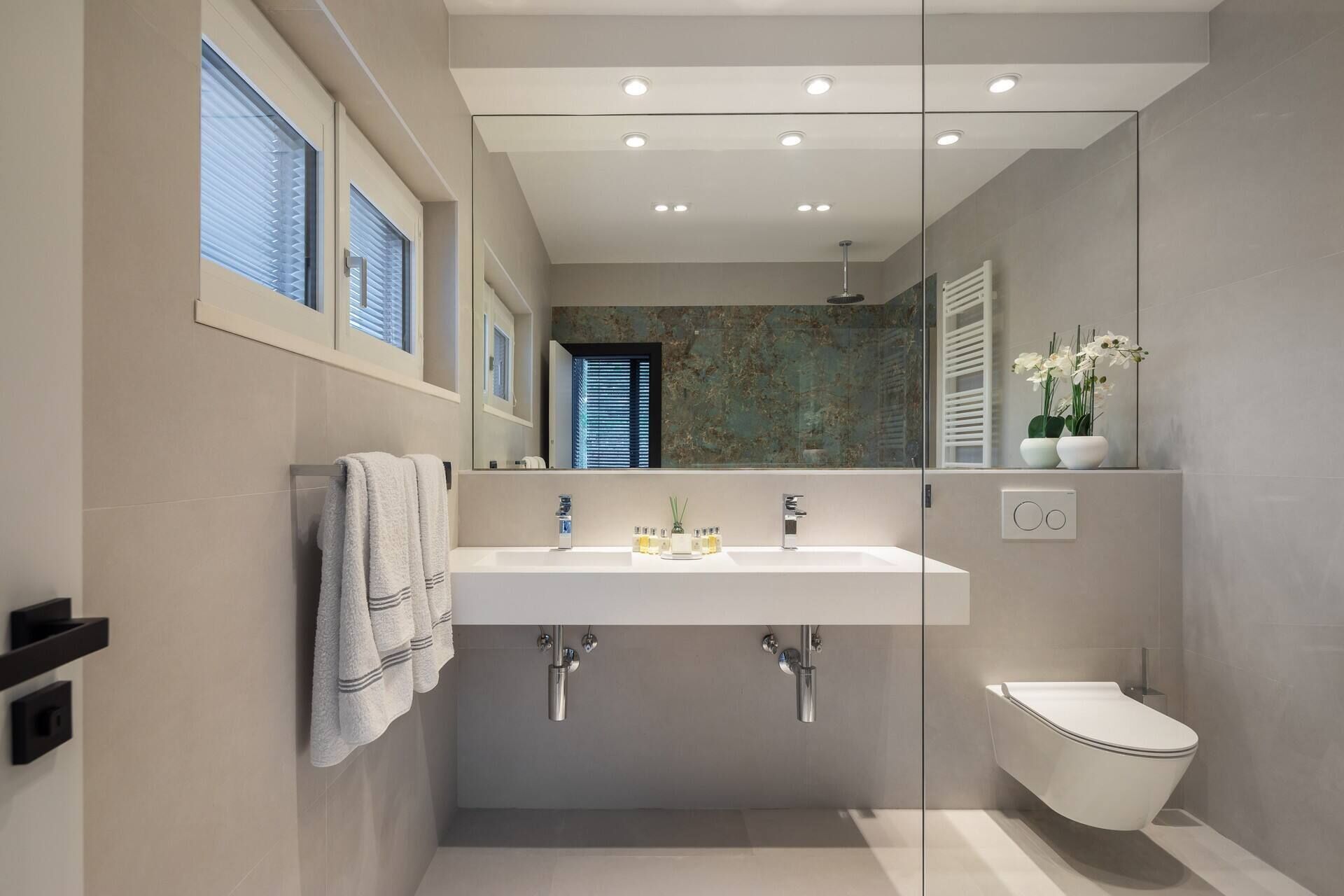 A modern bathroom with a large sink, a toilet, and a shower area.