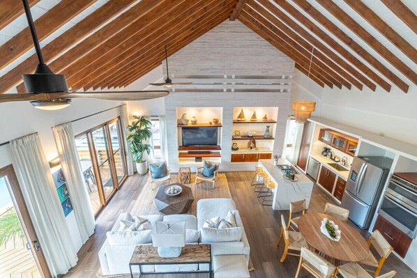 A spacious living area with a high ceiling, a dining table, and a kitchen with modern appliances.