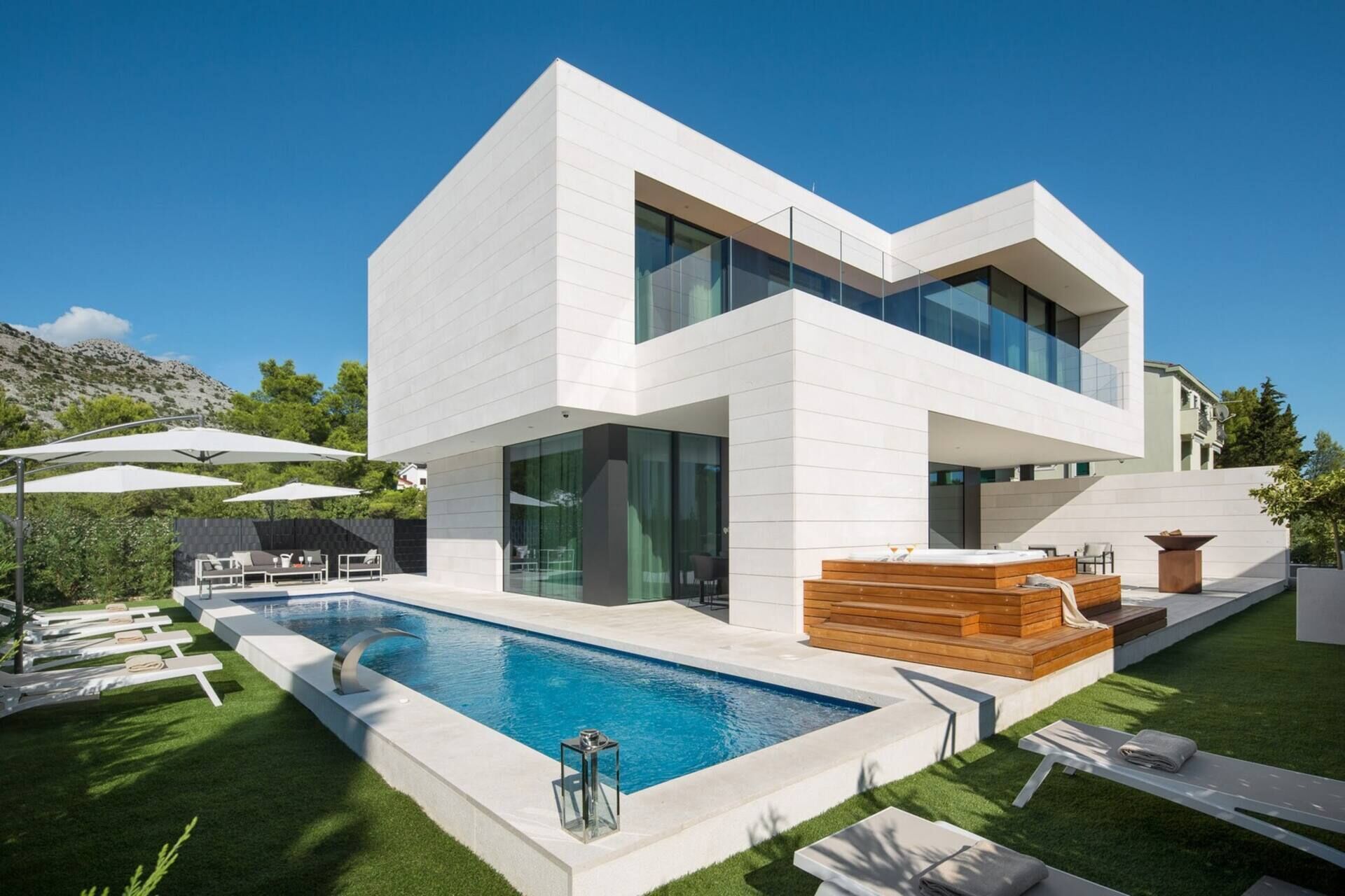 A modern two-story house with a swimming pool, outdoor seating, and a hot tub.