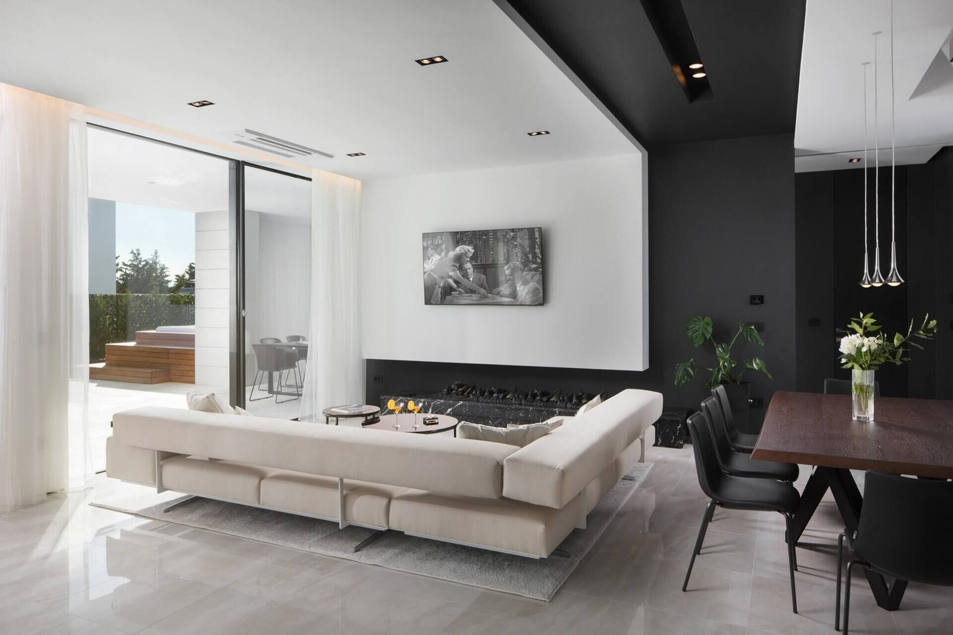 Ein modernes Wohnzimmer mit einem großen weißen Sofa, einem Esstisch mit Stühlen und einem Kamin.