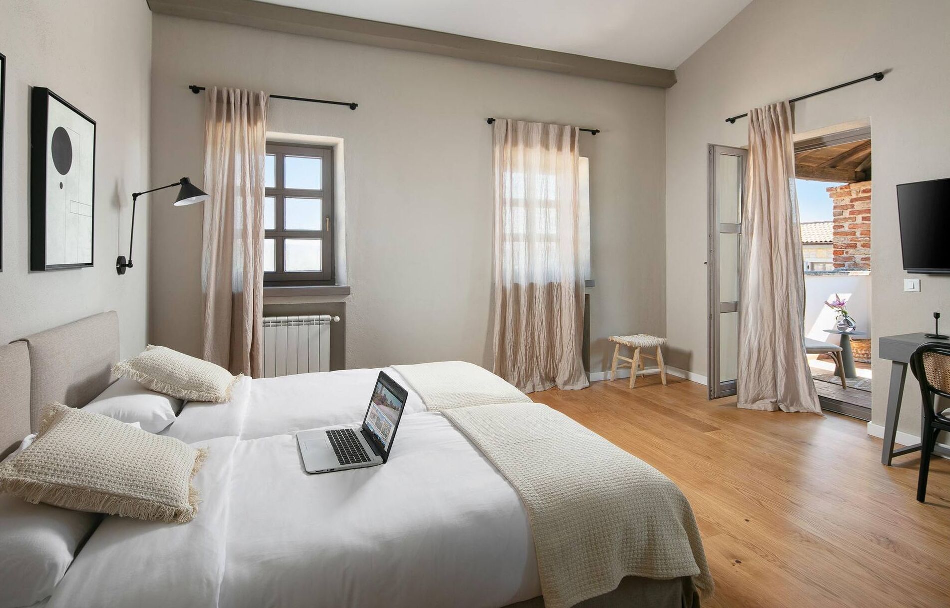A bedroom with a bed, a laptop, a window, and a balcony with a chair.