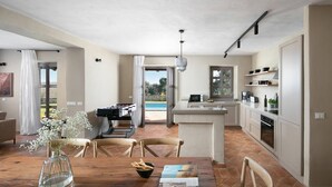 A modern kitchen with a central island, a dining area with a wooden table, and a view of a swimming pool. - Rustic Villa Clematis with a pool in Istri, panoramic view, pet friendly (Sveti Lovrec)