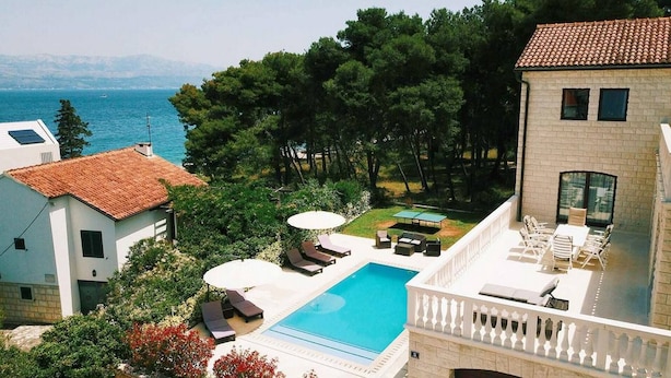 A pool area with lounge chairs, a table, and a view of the sea. - Villa Clementine with pool, sea view, big group near sea pet friendly bbq family (Sutivan)