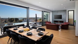 A modern living room with a dining area, large windows, and a fireplace. - Luxury Villa Dali - 42 m2 infinity pool & wellness, family, stylish (Medulin)