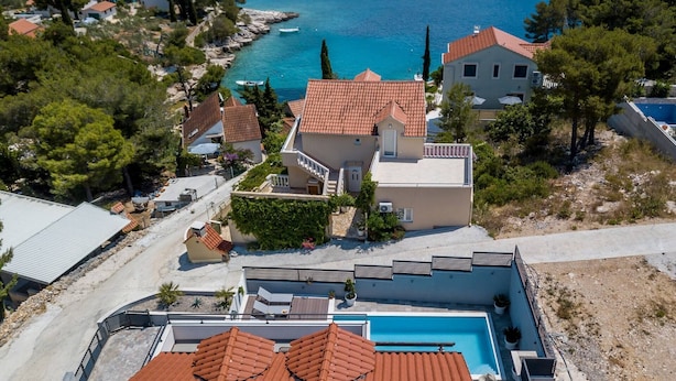 En fastighet vid kusten med en swimmingpool, en terrasserad trädgård och utsikt över havet.