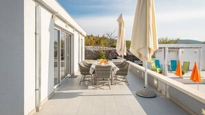 Une terrasse sur le toit, avec une table dressée pour le dîner, des chaises d’extérieur et des parasols.