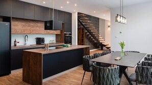 A modern kitchen with a central island, dark cabinetry, and a wooden staircase. - Villa Golden Ananas, 45 m2 headet pool, sea view (Sutivan)