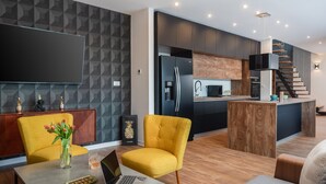 A modern kitchen with a built-in oven, microwave, and refrigerator. There is a dining area with a table and chairs, and a living room with a sofa and a coffee table. - Villa Golden Ananas, 45 m2 headet pool, sea view (Sutivan)