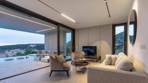 A modern living room with a large TV, comfortable seating, and a view of the city.