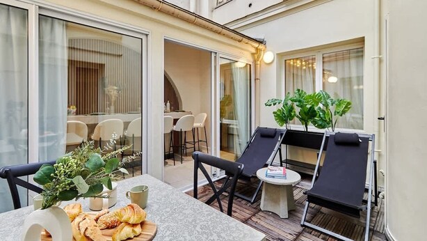 A sunlit patio with a dining table, chairs, and lounge chairs. - Terrace apartment Trocadero Eiffel Tower (Paris)