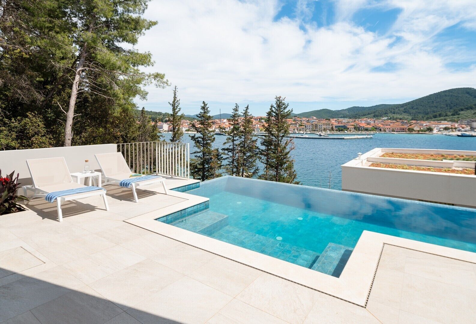 Una piscina privata con due lettini prendisole e vista su una località costiera.