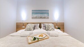 A neatly made bed with a tray of croissants and a cup, two pillows with leaf patterns, and a painting of a beach scene on the wall. - Excellent Villa Oasis with a pool, bbq, quiet area, family, gym (Grizane)