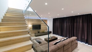 A modern living room with a staircase, a sofa, a coffee table, and a TV. - Excellent Villa Oasis with a pool, bbq, quiet area, family, gym (Grizane)