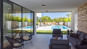 Un espacio exterior moderno con piscina, puertas de cristal y vistas a un jardín exuberante.