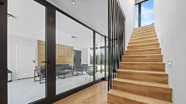 Un interior moderno con una escalera de madera que lleva a una puerta de cristal.
