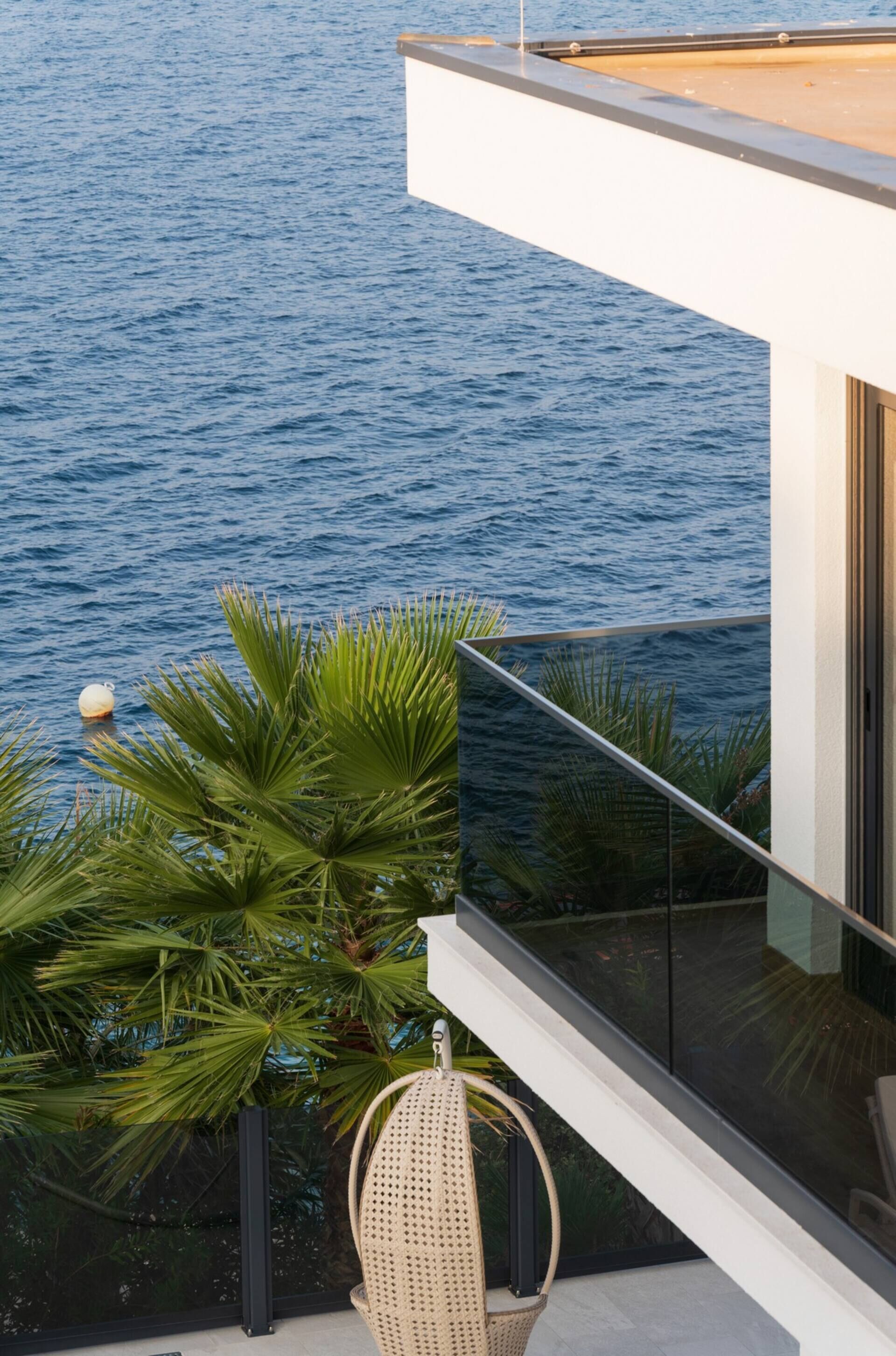 A modern balcony with a glass railing overlooking a body of water.