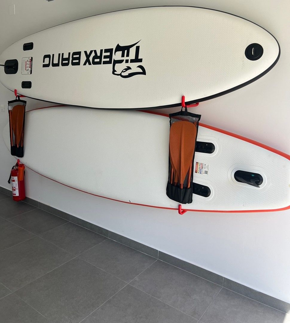 Twee surfplanken aan een muur bevestigd, vastgezet met banden.