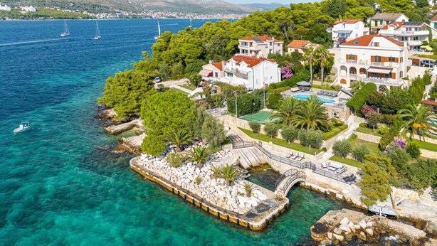 Una propiedad costera con piscina, un puente de piedra y vistas al mar.