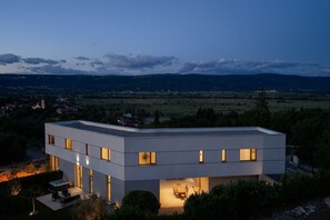 A modern building with multiple windows, a flat roof, and a patio area with outdoor furniture.