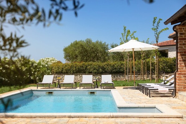 A swimming pool with lounge chairs and umbrellas, surrounded by greenery and a stone wall. - Rustic Villa Ruta with a pool in Istri, panoramic view, pet friendly (Sveti Lovrec)