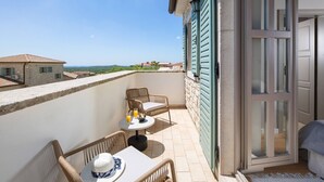 A balcony with wicker furniture, a table with drinks, and a view of the sea and buildings. - Rustic Villa Ruta with a pool in Istri, panoramic view, pet friendly, quite area, family, private parking, terrace, fancy yard (Sveti Lovrec)