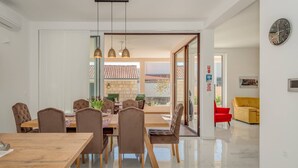 A modern dining area with a wooden table and chairs, a glass partition, and a view of the outside.