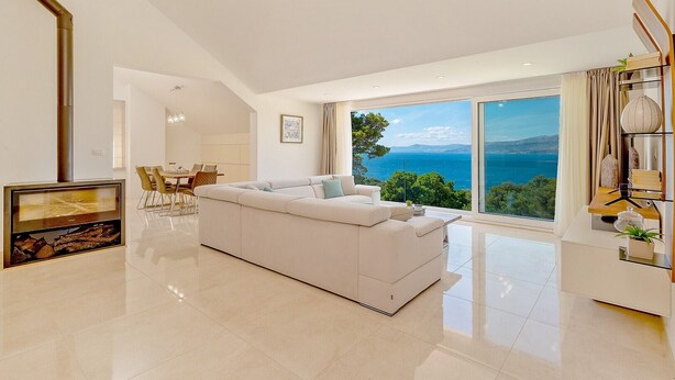 A spacious living room with a large white sofa, a dining area, and a view of the sea. - Villa Joy - heated pool, 35 000 m2 of land, gym, family, quiet area, stylish (Pucisca)