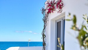 A balcony with a view of the sea, a potted plant, a table with a plate of food, a glass of wine, and a bottle of wine. - Casa di Recente Ristrutturazione, in Locazione Turistica, a due Passi dal Mare (Puglia)