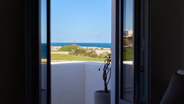 A hotel room with a bed, a bedside table, and a view of the sea through an open door. - Casa di Recente Ristrutturazione, in Locazione Turistica, a due Passi dal Mare (Puglia)