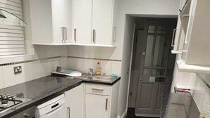 A kitchen with white cabinets, a black countertop, and a dishwasher. - Garden flat in central Hove, close to the beach, shops, bars and restaurants (Brighton and Hove)