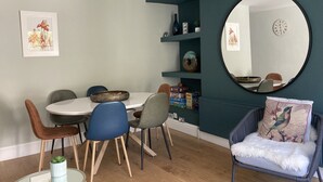 A dining area with a round table, chairs, and a decorative bowl. There is a mirror on the wall and a chair with a cushion. - Garden flat in central Hove, close to the beach, shops, bars and restaurants (Brighton and Hove)