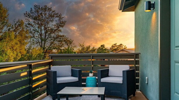 An outdoor patio with wicker furniture and a table, a small blue stool, and a decorative pineapple.