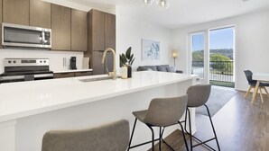 Una cocina moderna con una isla grande, electrodomésticos de acero inoxidable e iluminación colgante.