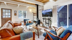 A cozy living room with a fireplace, comfortable seating, and a large TV. - Hot tub + Pool Table + Good Vibes (South Lake Tahoe)