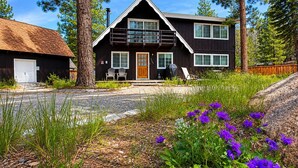 A two-story house with a front porch, a garage, and a small garden with purple flowers. - Hot tub + Pool Table + Good Vibes (South Lake Tahoe)