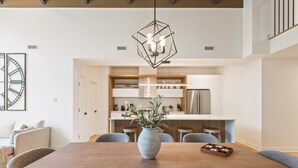 A modern kitchen with white cabinets, a central island, and a hanging light fixture. - Tremblant Prestige - Verbier 14-202 (Mont-Tremblant)