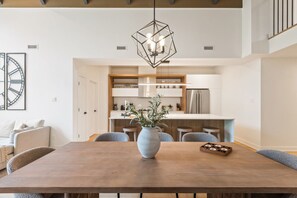 A modern kitchen with white cabinets, a central island, and a hanging light fixture. - Tremblant Prestige - Verbier 14-202 (Mont-Tremblant)