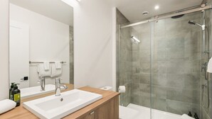 A modern bathroom with a large mirror, two sinks, a shower enclosure, and a toilet. - Tremblant Prestige - Verbier 14-202 (Mont-Tremblant)
