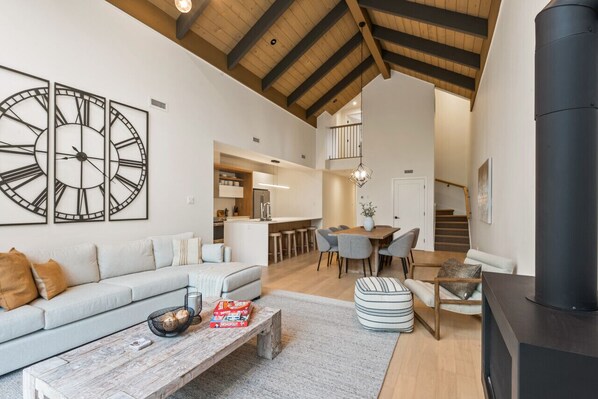 A spacious living area with a high ceiling, a fireplace, and a dining area with a kitchen in the background. - Tremblant Prestige - Verbier 14-202 (Mont-Tremblant)