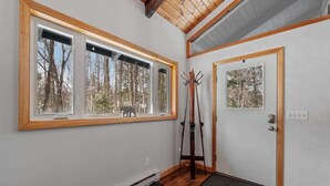 A room with a large window, a door, a coat rack, and a bench.