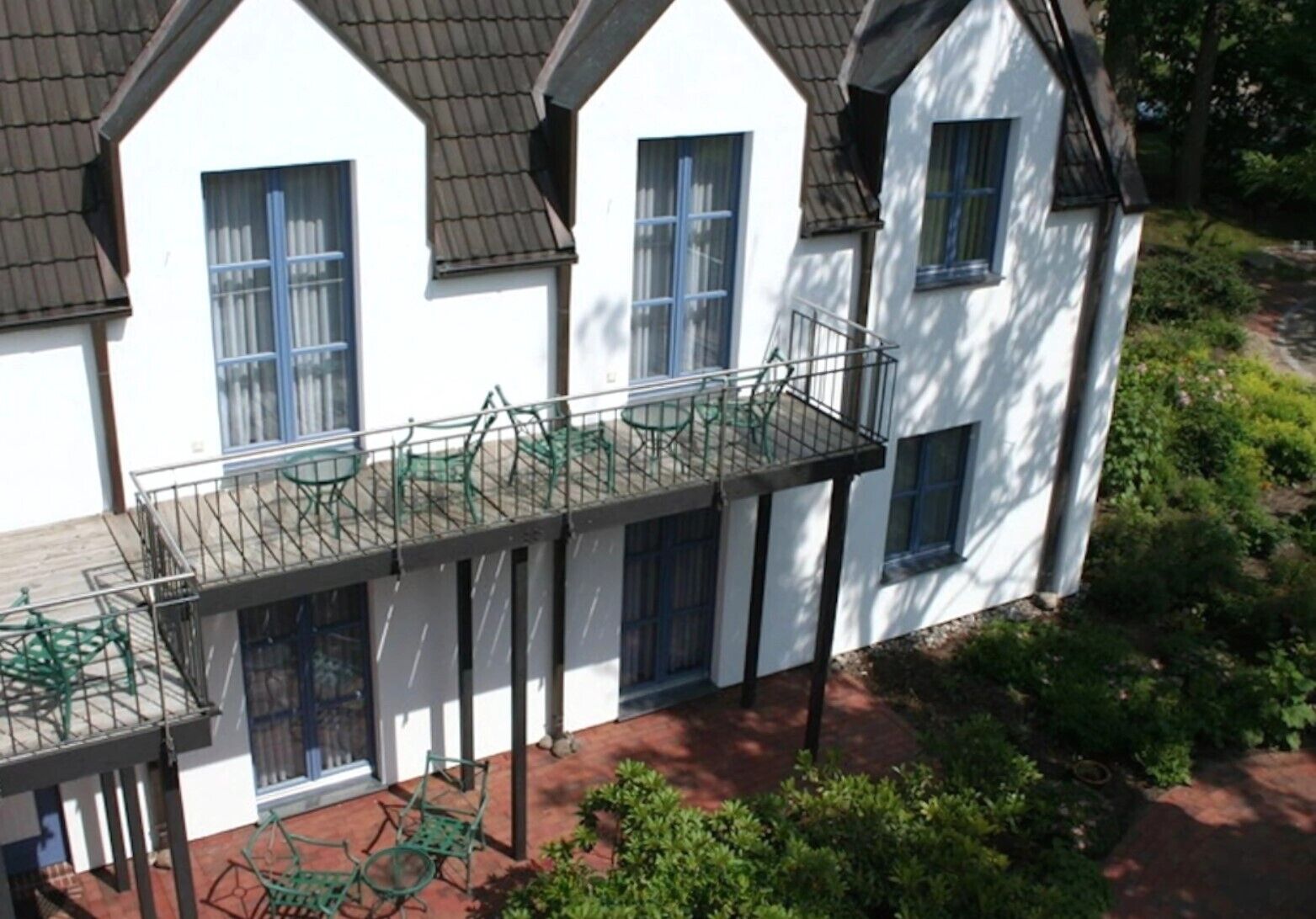 Una casa blanca con balcón, techo de tejas y jardín.