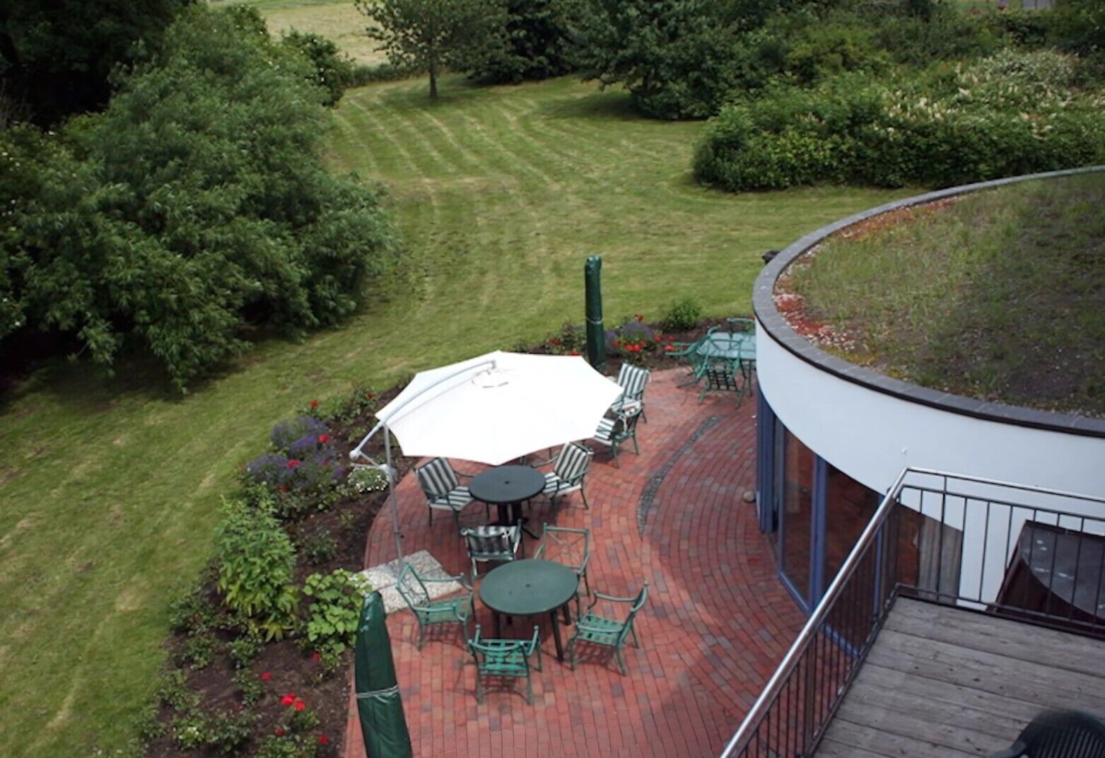 A patio area with a round table and chairs, a large umbrella, and a brick deck.