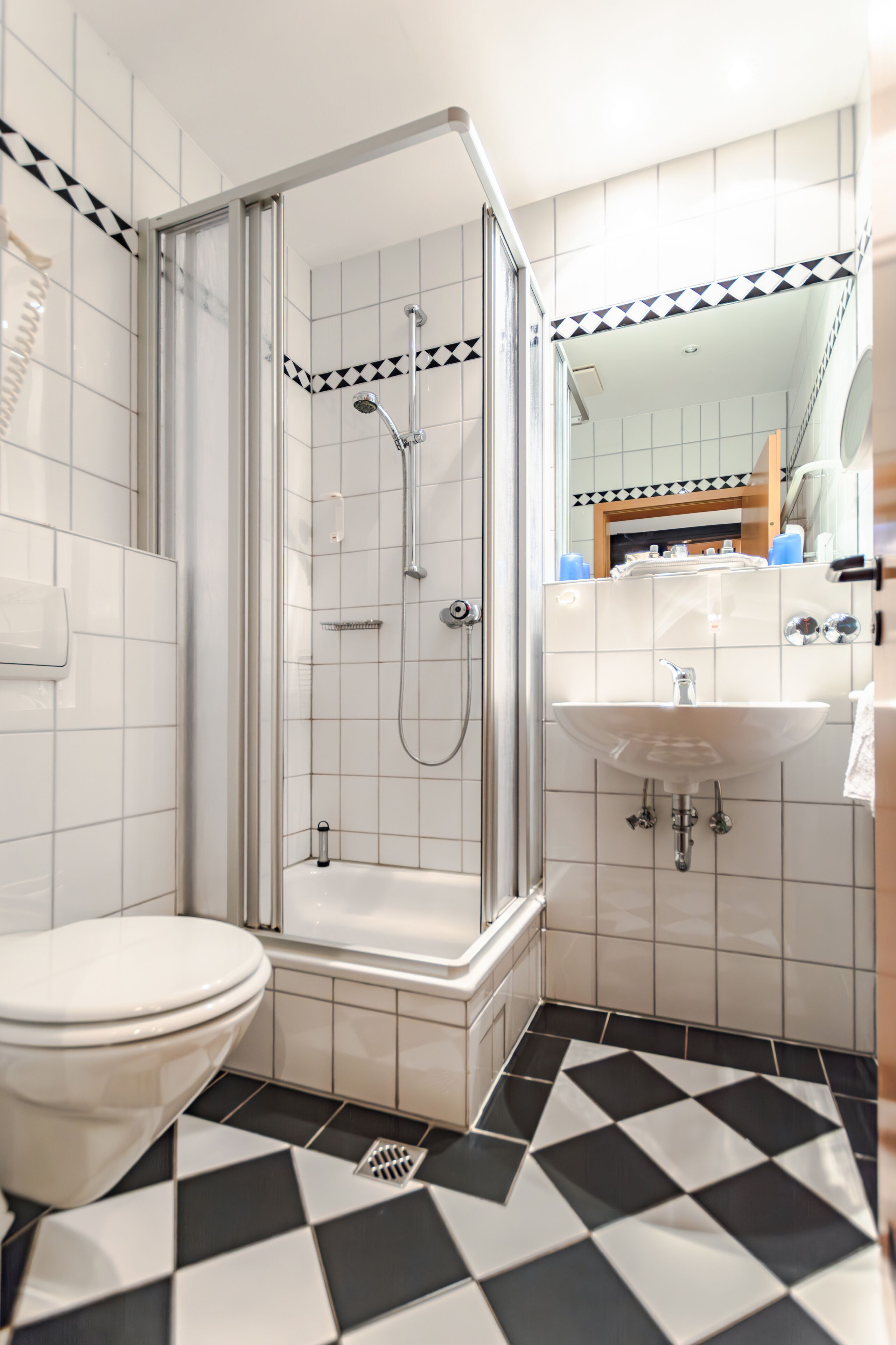 Une salle de bain équipée d’une douche, de toilettes, d’un lavabo et d’un sol carrelé.