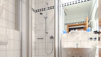 Une salle de bain équipée d’une douche, de toilettes, d’un lavabo et d’un sol carrelé.
