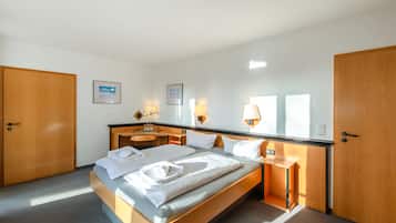 Una habitación de hotel con una cama grande, armario de madera, mesitas de noche y lámparas de pared.